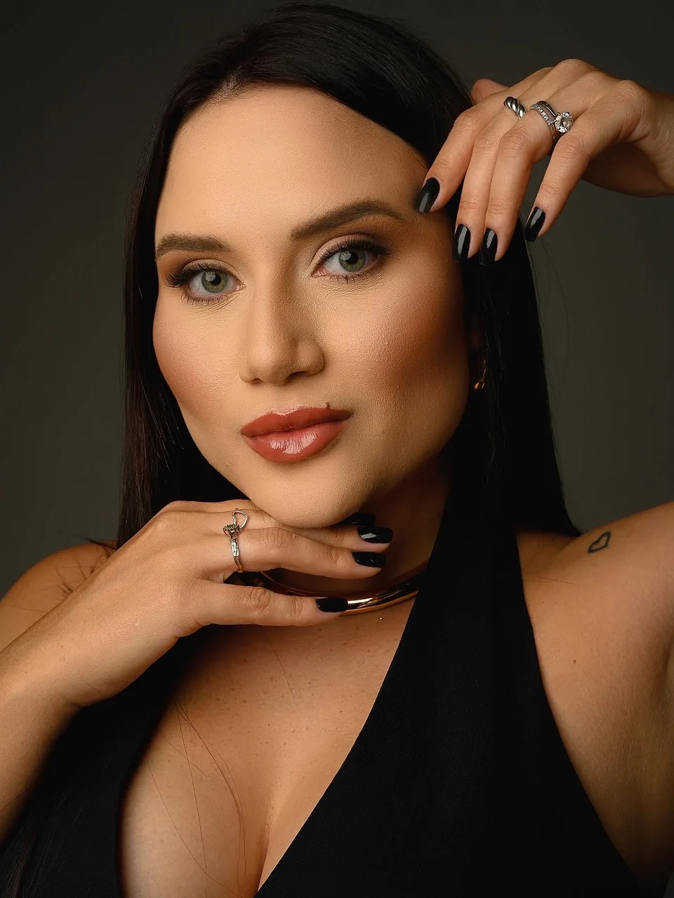Retrato de estúdio da Dra. Lorena Ferreira, com a mão junto ao rosto
